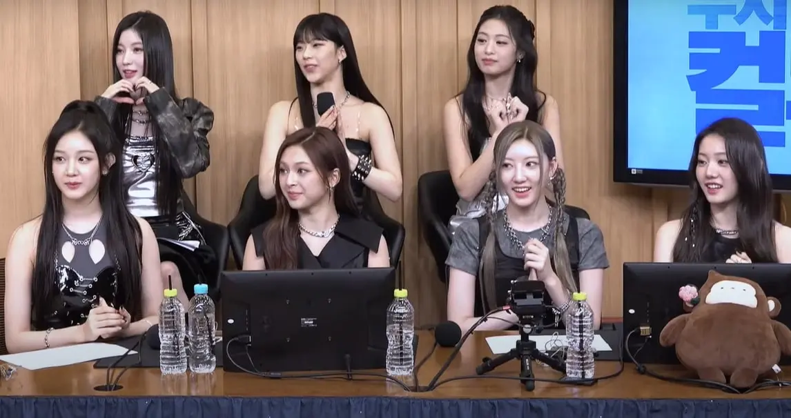 BABYMONSTER members sitting at microphones in a radio studio