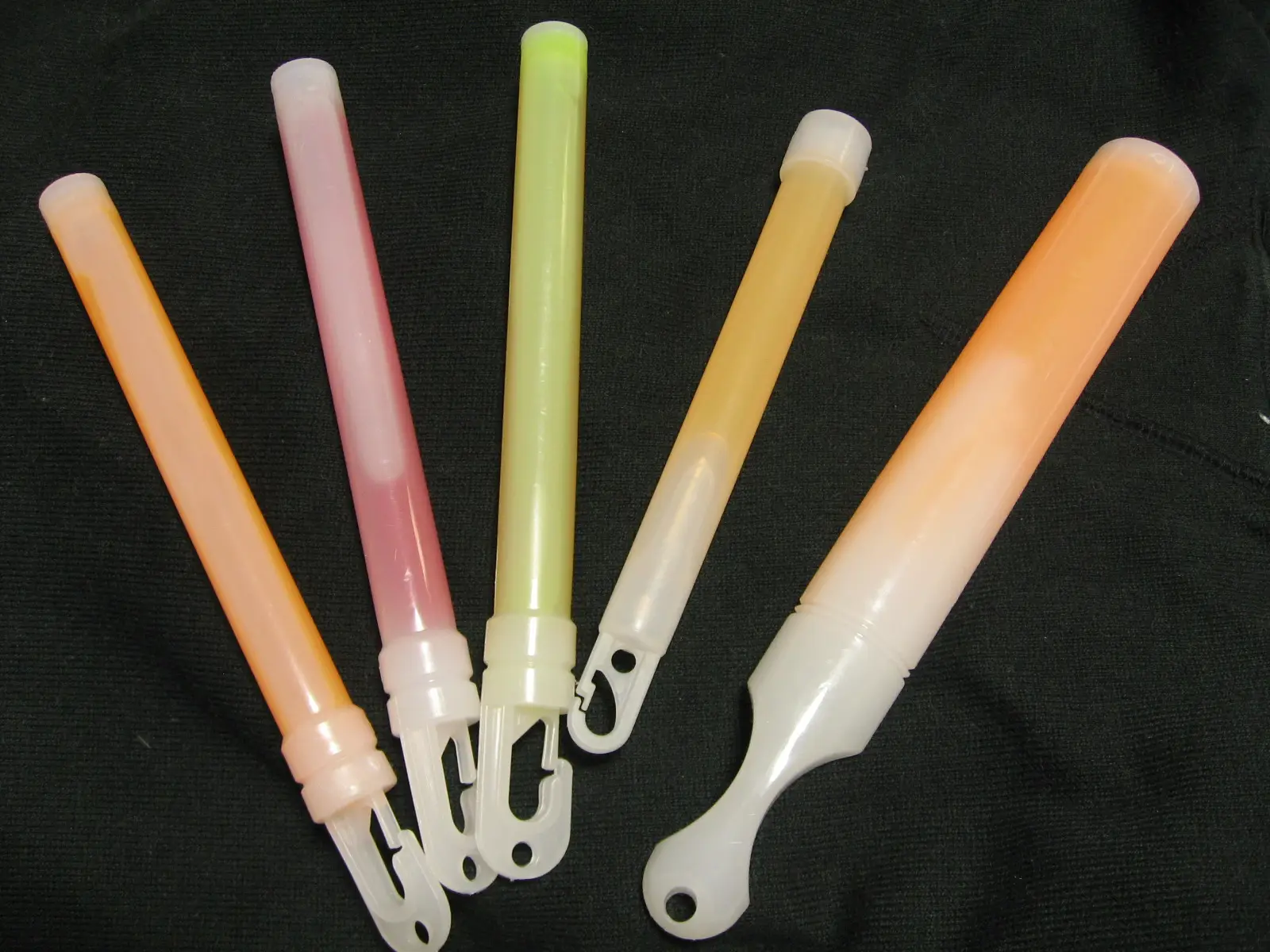 Five pastel glow sticks lined up on a dark cloth