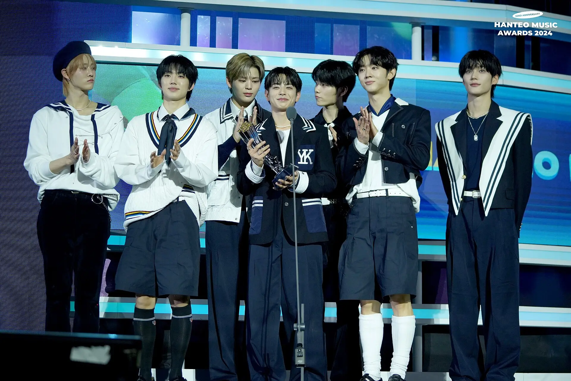 EVNNE members in navy and white outfits standing together on an awards show stage