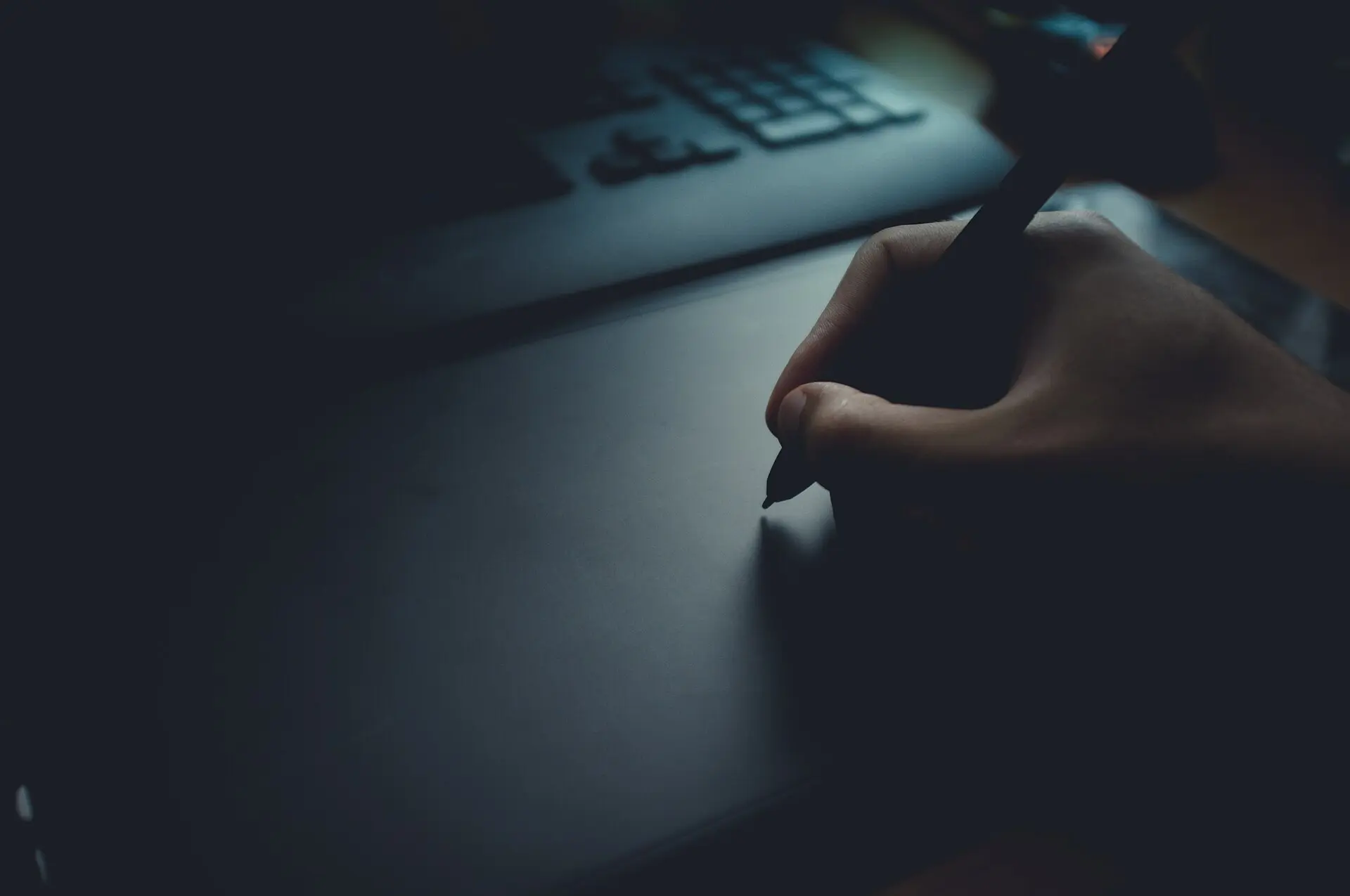 A hand drawing with a stylus on a graphics tablet in low light