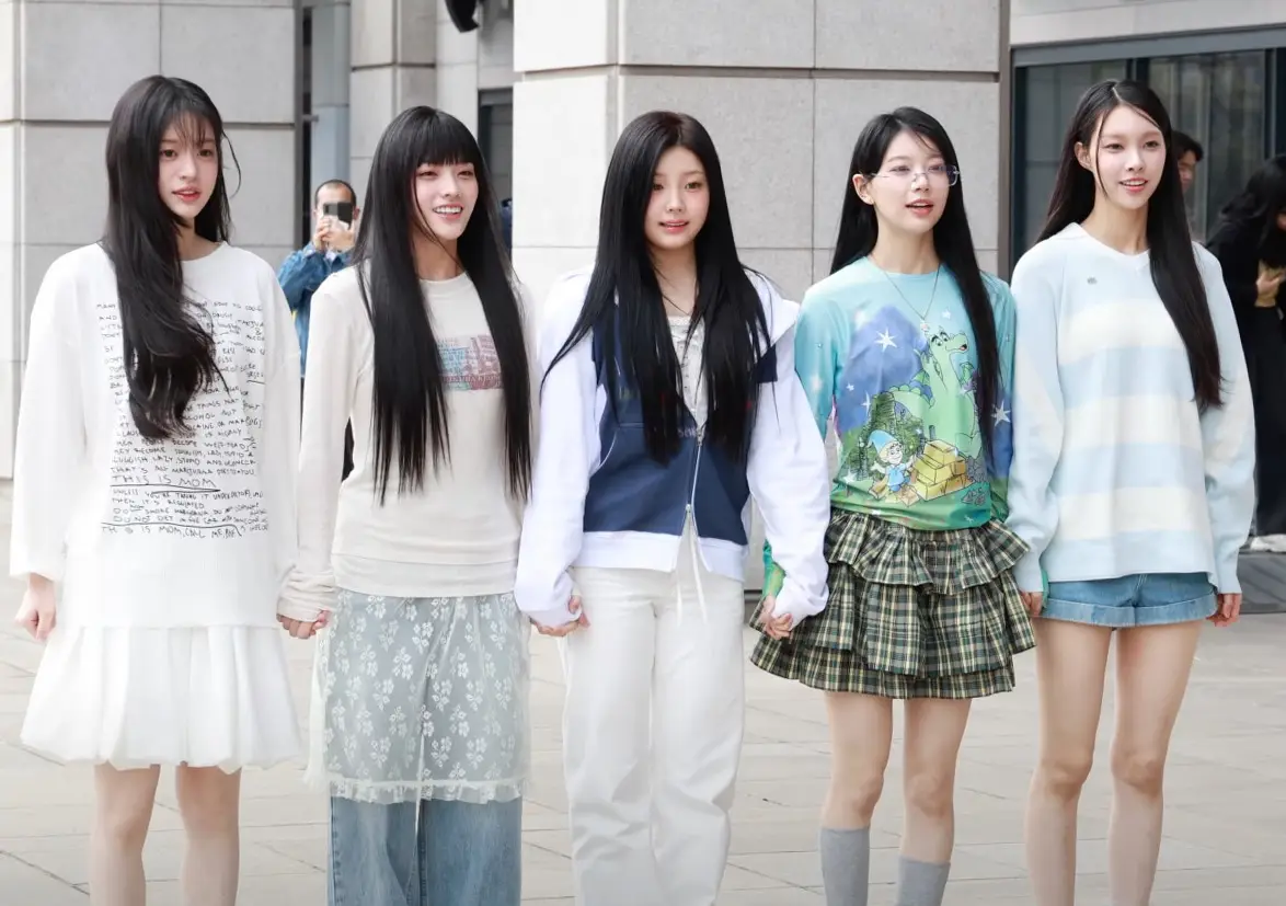 ILLIT's five members standing together outside a radio station in Seoul
