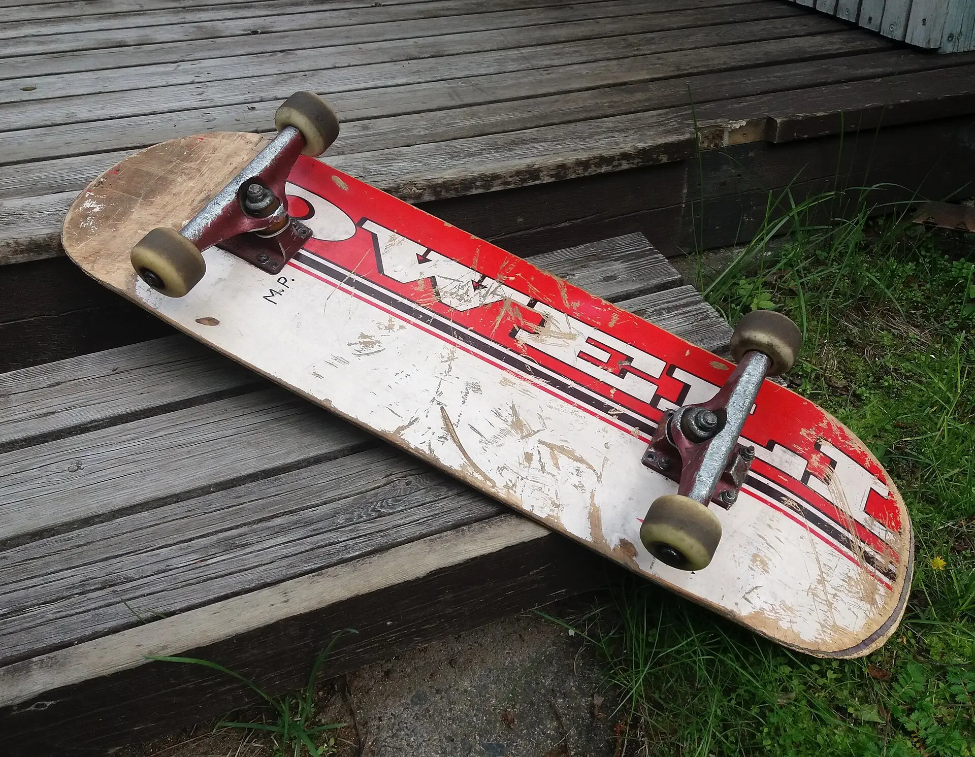 A worn red and white skateboard resting on wooden steps