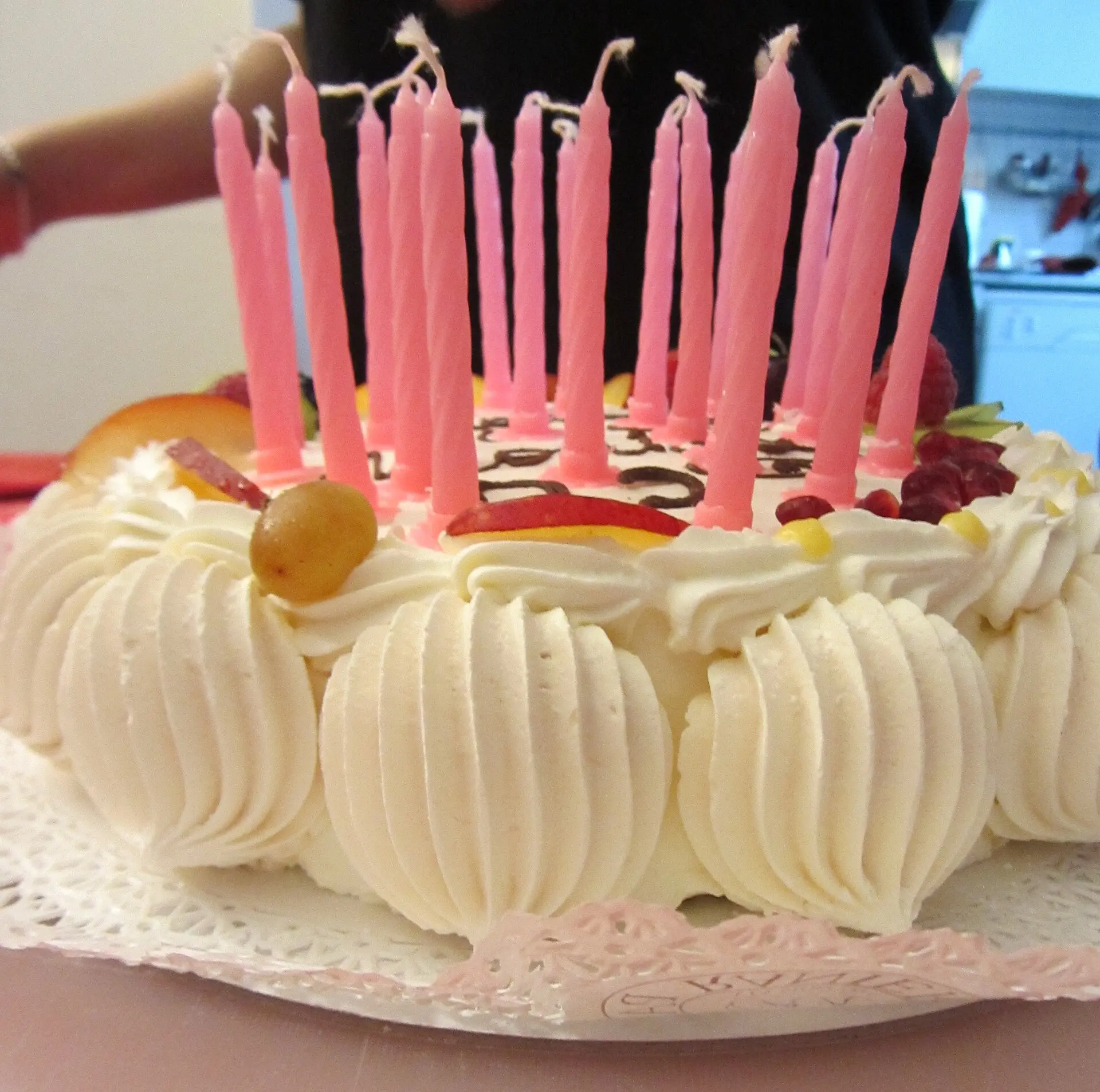 A cream birthday cake topped with pink candles