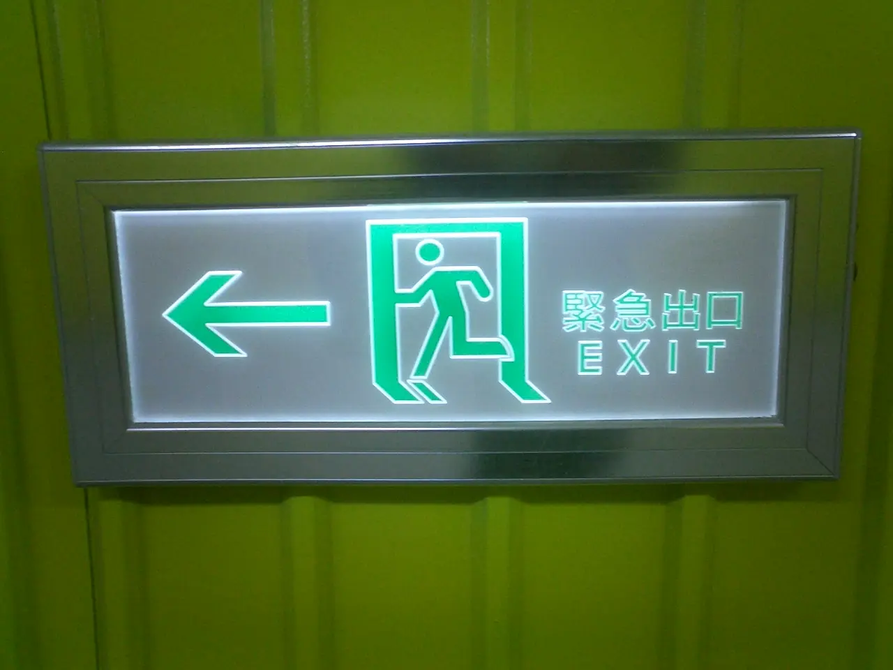 A green emergency exit sign with an arrow and a running figure