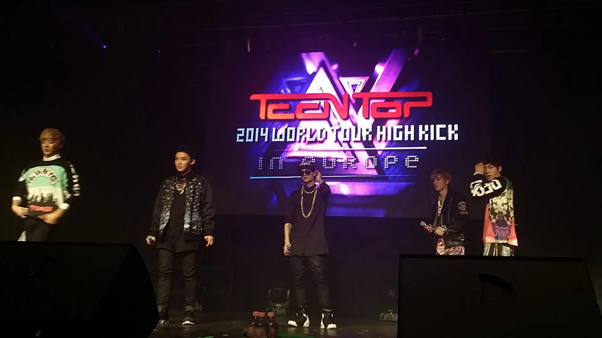 TEEN TOP performing on stage in front of a glowing tour logo
