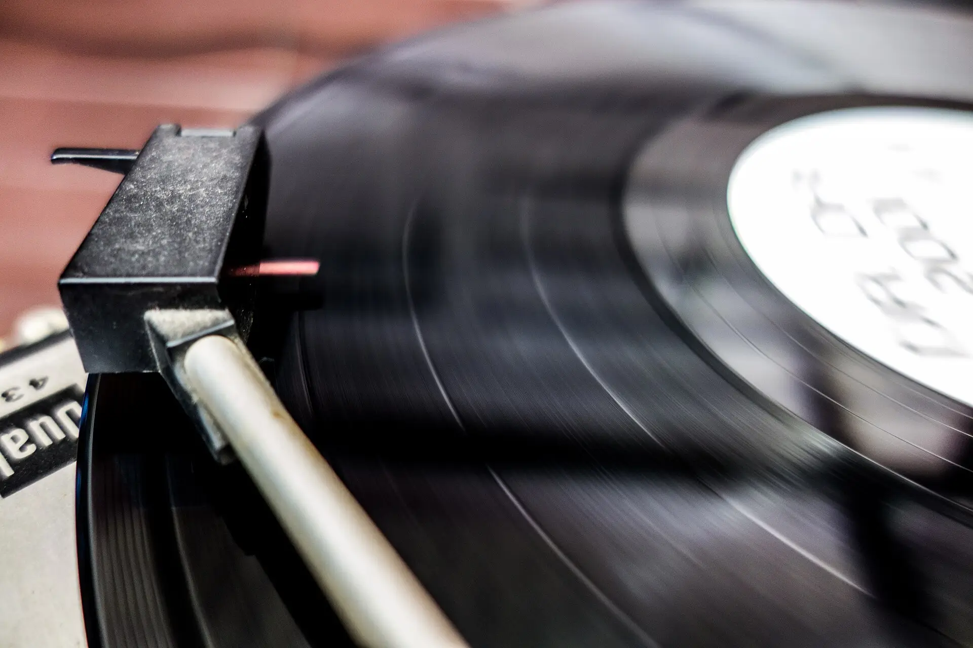A turntable tonearm playing a spinning black vinyl record